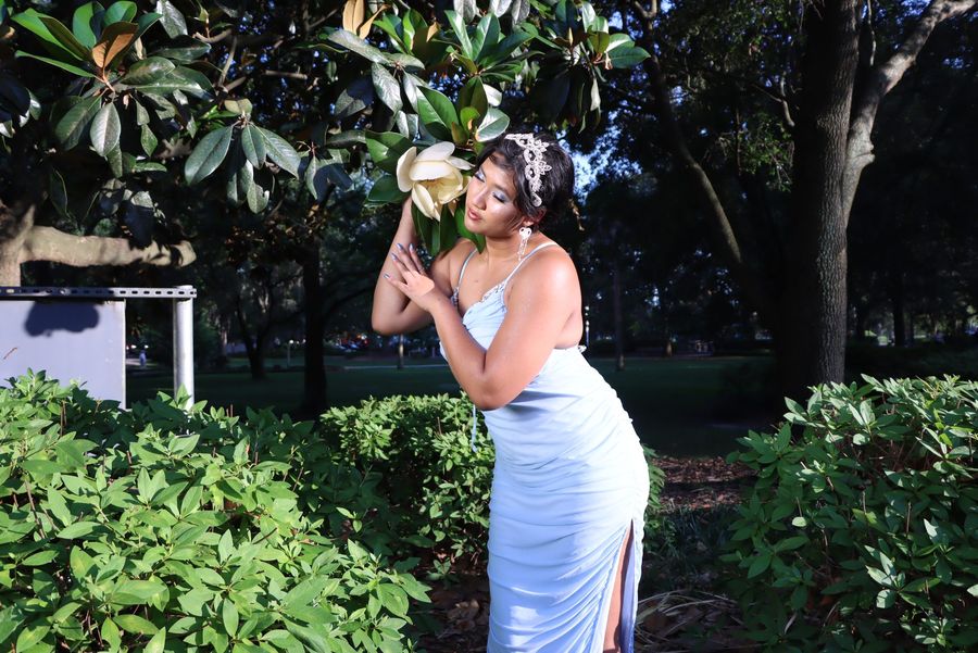 Zabethah in a light blue gown holding a magnolia blossom